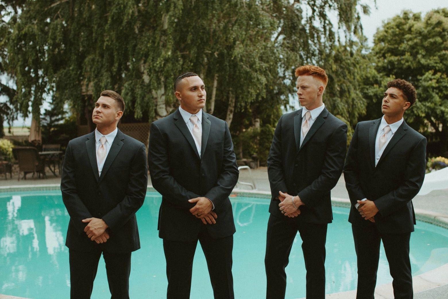 groomsmen wearing tuxedos by stone ridge estates wedding venue swimming pool